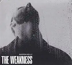 A black-and-white image of a man looking up as water falls on a glass window in front of him. The artist's name and album title appear on the lower left corner of the cover, colored in white.