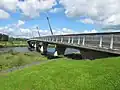 a view from a nearby bank of a curved road bridge