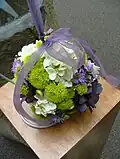 A pomander bouquet, shaped completely round and worn by a ribbon on the wrist.
