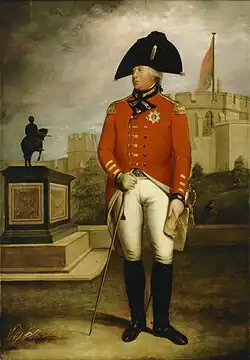 Portly man holds a sword, wears a bright red coat, and a big black hat.